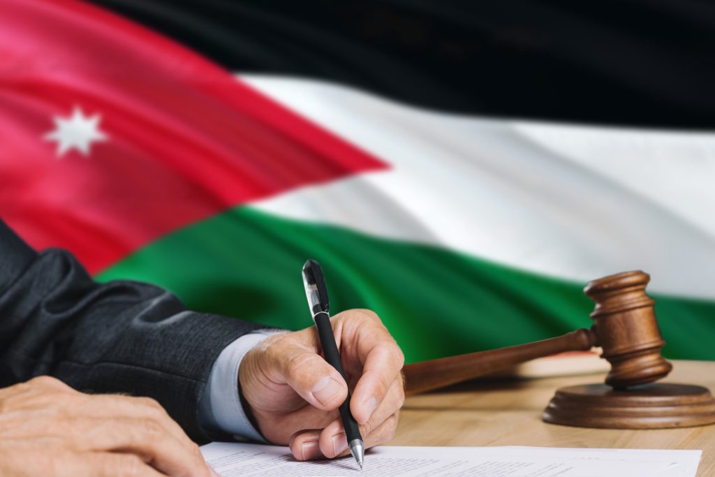 The Jordan flag, a gavel, and a man signing a document