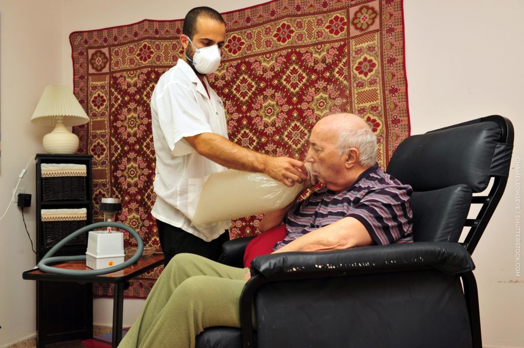 A doctor helping an old man breathe into a bag