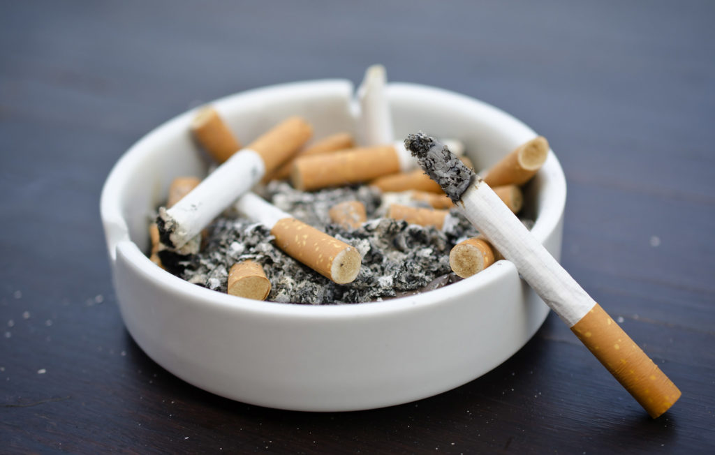 An ashtray with cigarette butts and a cigarette