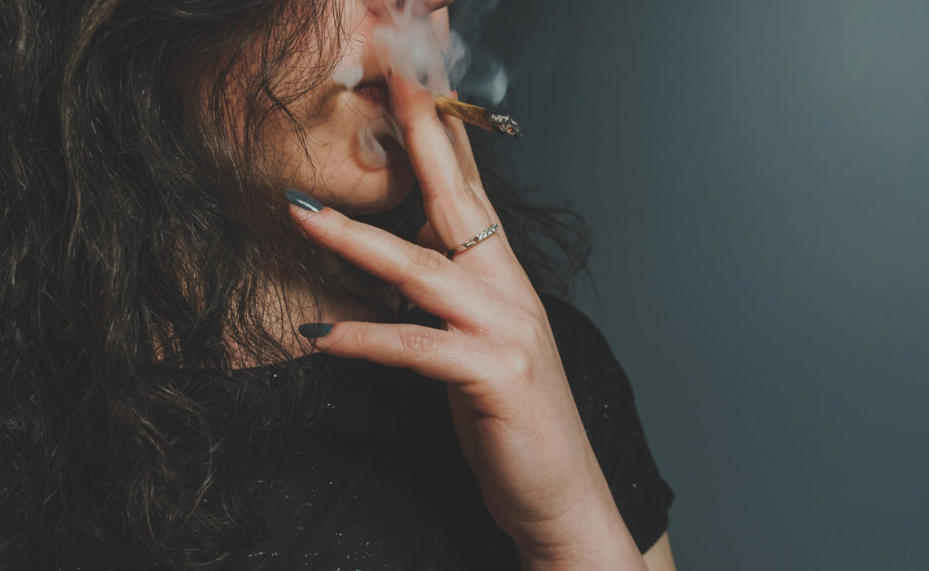 A woman with brown hair smoking a joint