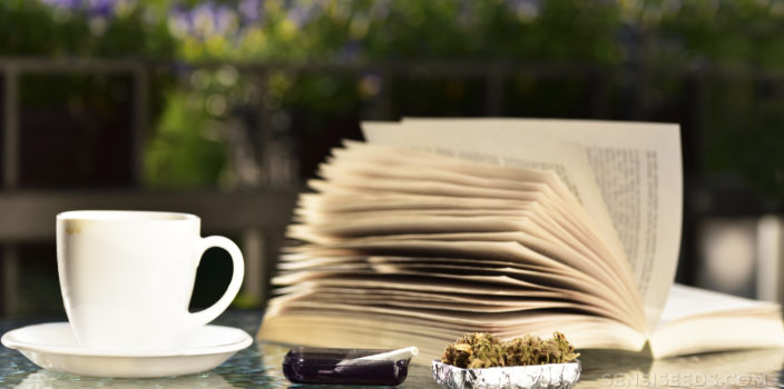 Mesa de café con un libro, taza de café, cenicero con articulación y taza con cannabis seco