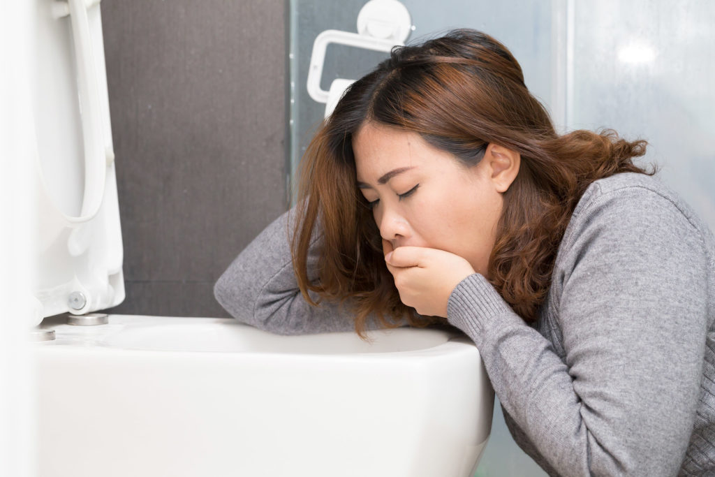 Une femme avec des nausées assises devant le siège des toilettes