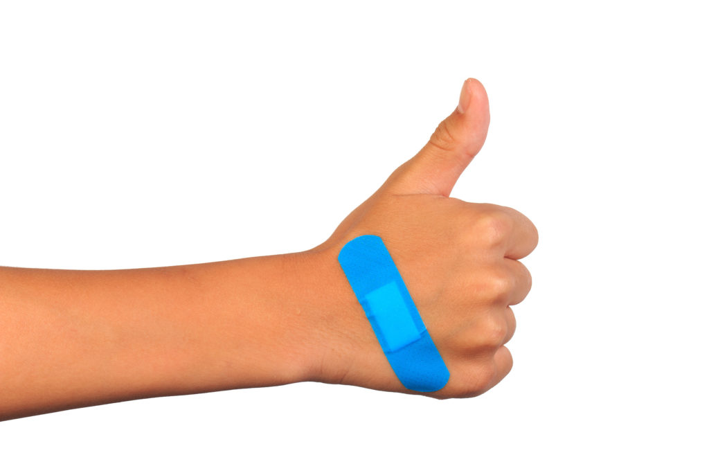 A person holding thumb up with a blue patch