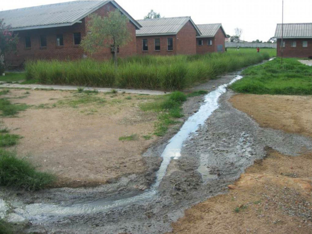 Ruwe rioolwater stroomt voorbij een school in Zimbabwe