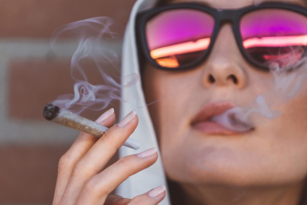 A woman wearing sunglasses and smoking a joint