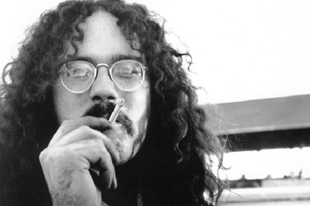 A black and white photo of John Sinclair smoking a cigar 