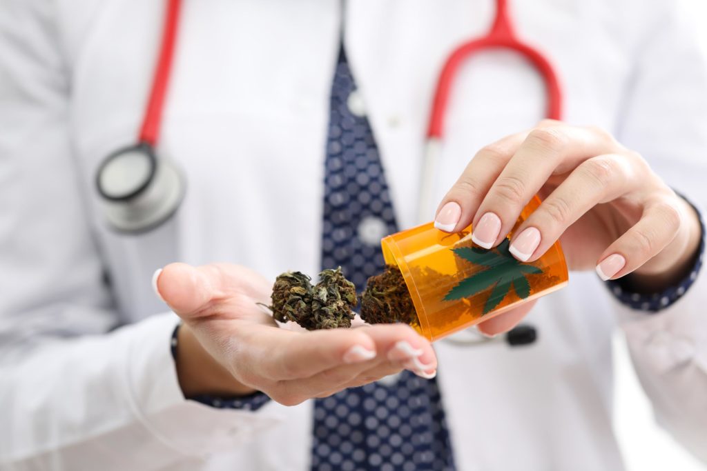 A person with stethoscope holding medicinal cannabis and a medical container