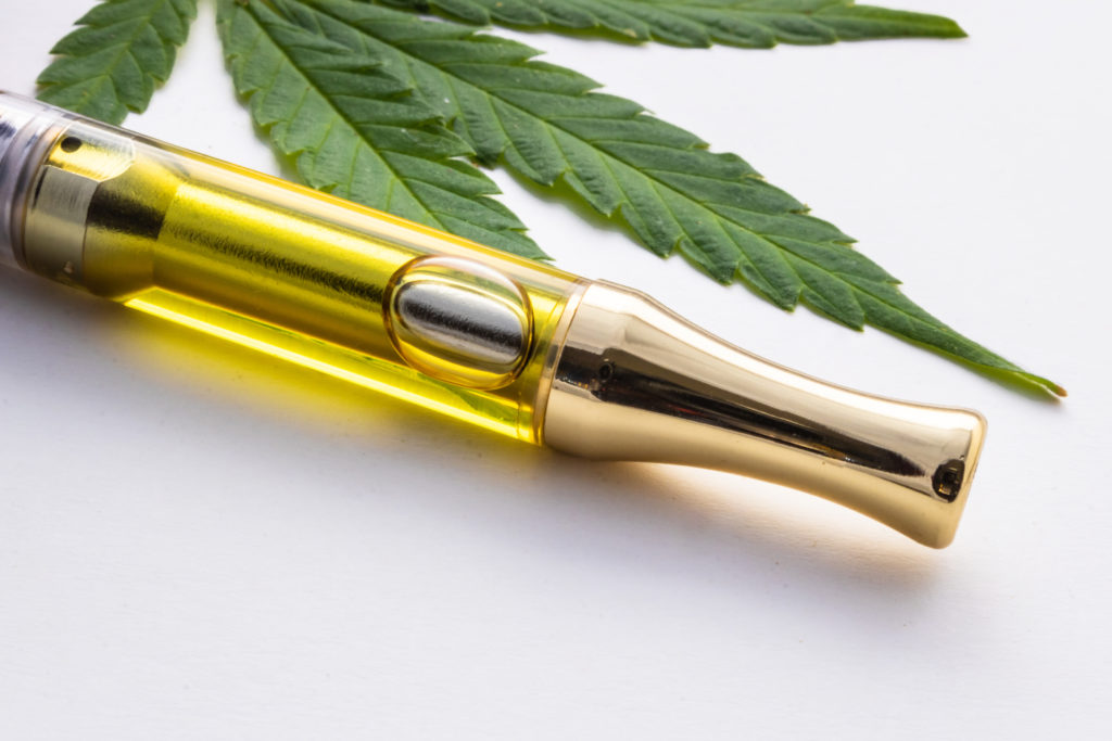 E-cigarette with oil and a cannabis leaf beside