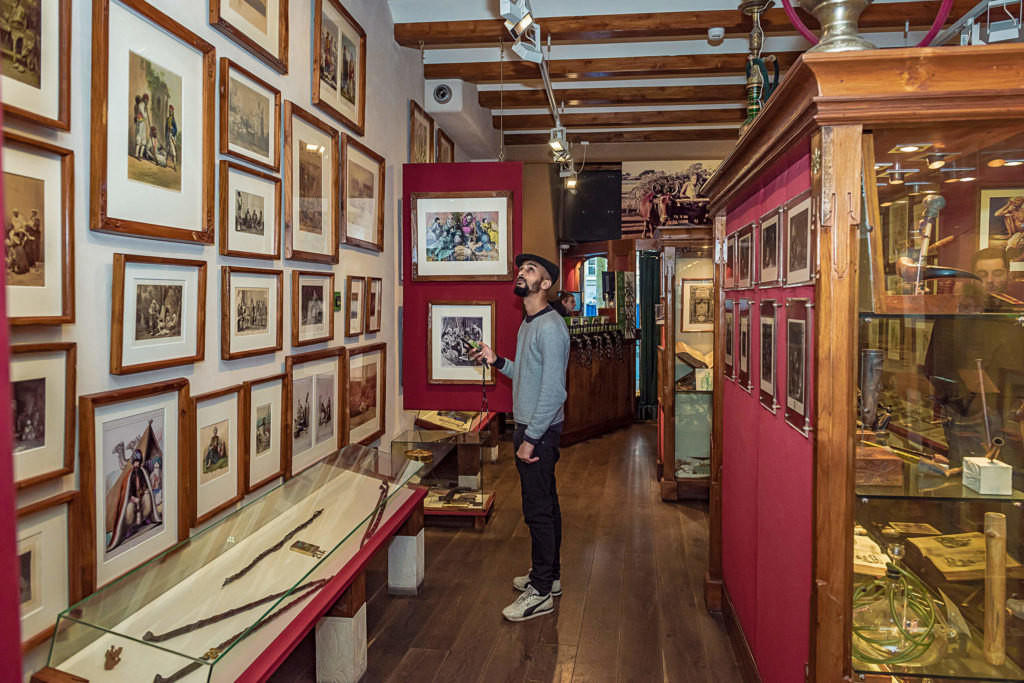 A man looking up at framed pictures on the wall inside the museum