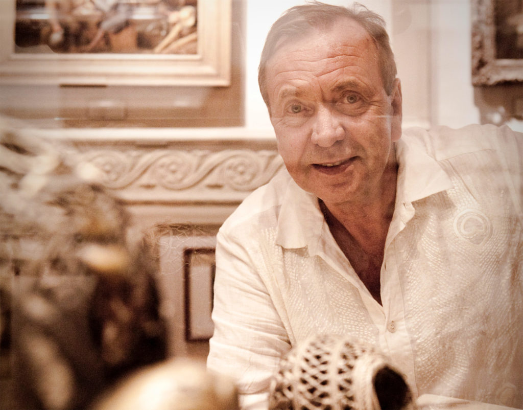 A man smiling on the other side of a museum display cabinet