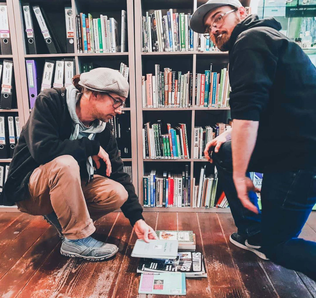 Two men looking at different books from the Cannabis College