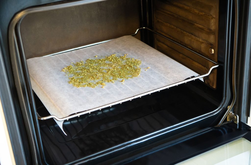 Dried cannabis flowers on parchment paper in the oven