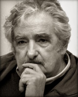 A black and white portrait photograph of Jose Mujica holding his hand up to his chin