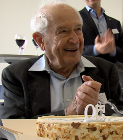 Professeur Raphael Mechoulam souriant. Un gâteau d'anniversaire avec le numéro 50 est devant lui.